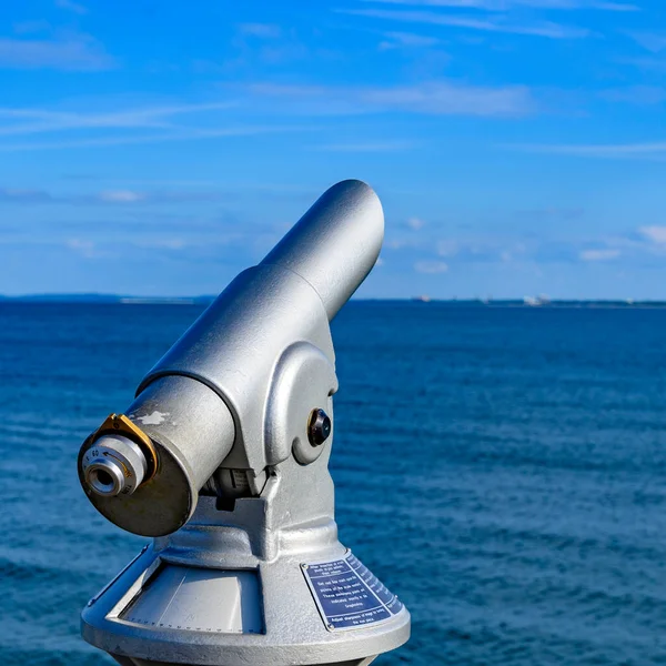 Telescope with coin slot on the pier in Bansin on the island of Usedom in Germany. Sea and sky are dark blue and radiate in the sunshine.