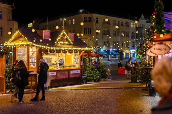 Berlin, Almanya - 20 Aralık 2019: Küçük bir Berlin Noel pazarında gece sahnesi, pazar tezgahları ve bir sürü ışıklandırması olan her türlü dekorasyonla.
