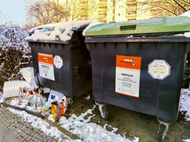 Berlin, Almanya - 31 Ocak 2021: Berlin 'deki bir atık şirketinin kar kaplı geri dönüşüm konteynırının yakınındaki cam atığı.