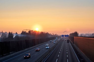 Berlin, Almanya - 8 Şubat 2018: Şiddetli turuncu güneş ışığıyla sisli bir sabahta Berlin 'de bir otoyolun üzerinde gün doğumu