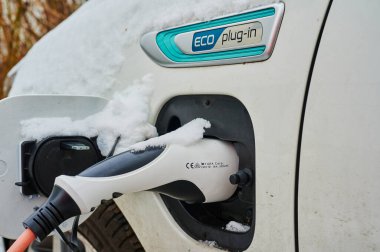 Berlin, Almanya - 6 Şubat 2021: Şarj prizinde kar olan hibrit elektrikli bir araca bakın.