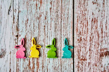 Tahta bir masada dört renkli Paskalya tavşanı.