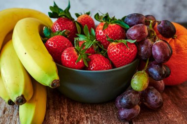 Tahta bir masanın üzerinde, güneş ışığında duran taze meyve..