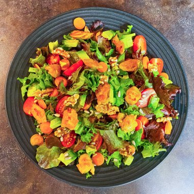 Marul, domates, havuç, ceviz ve vejetaryen kümes hayvanlarından yapılmış taze salata tabağı..