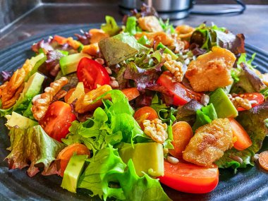 Marul, domates, havuç, ceviz ve vejetaryen kümes hayvanlarından yapılmış taze salata tabağı..