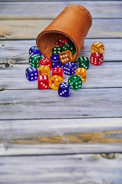 Blick Auf Verschiedenfarbige Spielwürfel Und Einen Würfelbecher Auf Einem Holztisch — Stockfoto