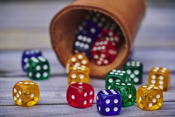 Blick Auf Verschiedenfarbige Spielwürfel Und Einen Würfelbecher Auf Einem Holztisch — Stockfoto