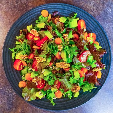 Marul, domates, havuç ve cevizden yapılmış taze salata tabağı..