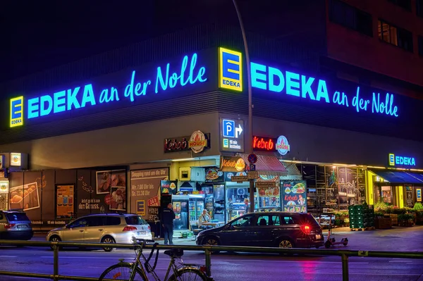 Berlin; Almanya - 23 Haziran 2021: Berlin şehir merkezinde aydınlatılmış bir süpermarketin köşesindeki açık büfenin gece çekimi.