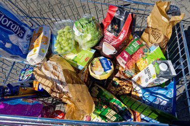 Berlin, Almanya - 9 Eylül 2022: Günlük ihtiyaçlar için çeşitli ürünlerle dolu bir alışveriş arabasına bakın.
