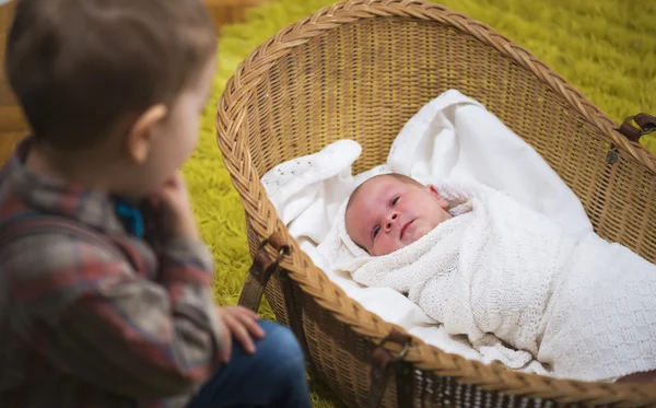 Küçük çocuk üzerinde yeni doğan bebek kardeşi izliyor — Stok fotoğraf