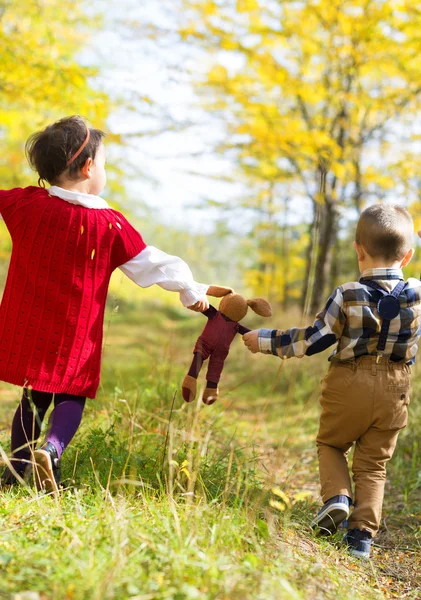 Bambina e ragazzo che camminano con il loro giocattolo preferito — Foto Stock