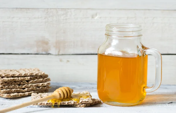 Miel avec une trempette et pain croustillant sur fond en bois — Photo