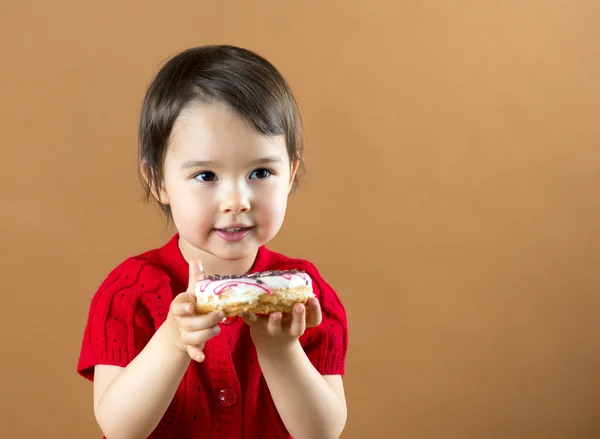 Mooi klein meisje donuts houden bij bruine achtergrond in de studio — Stockfoto