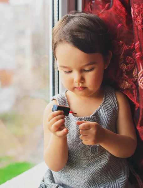 Küçük çocuk, şirin bebek kız evde renkli manikür yaparken oje ile oynarken eğleniyor — Stok fotoğraf