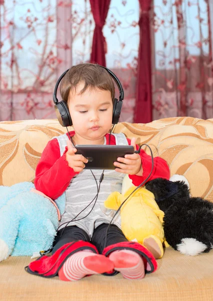 Bambina sul divano con auricolari e musica d'ascolto da smartphone — Foto Stock