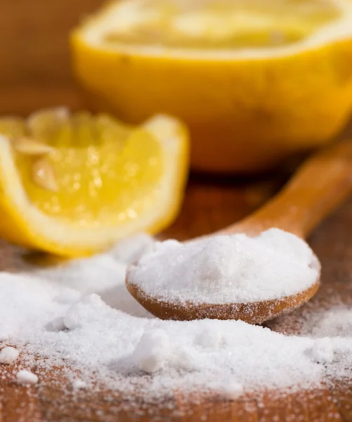 Baking soda (sodium bicarbonate) in a wooden spoon and lemon — Stock Photo, Image