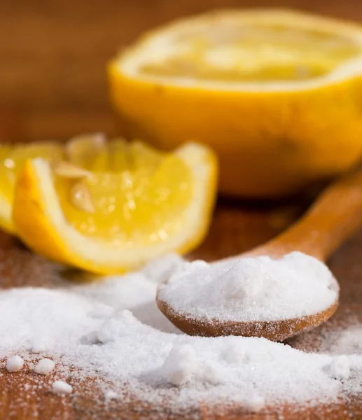 Baking soda (sodium bicarbonate) in a wooden spoon and lemon — Stock Photo, Image