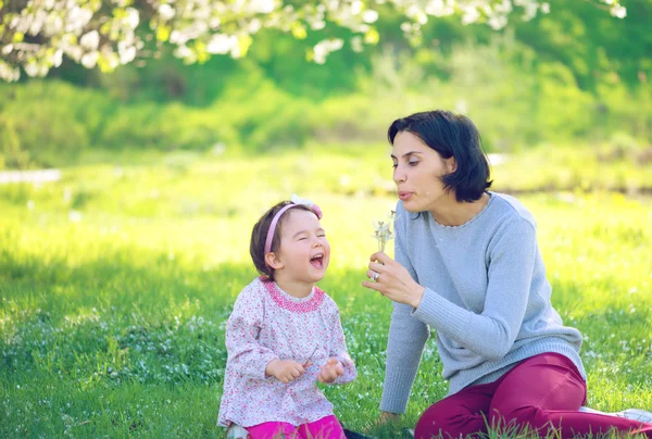 Glückliche junge Mutter und ihre Tochter pusten Seifenblasen im Park — Stockfoto