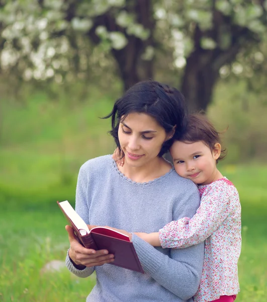 Mãe com filha ler um livro no prado — Fotografia de Stock