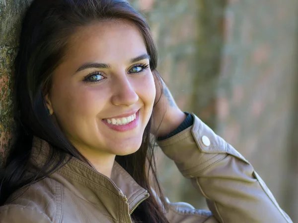 Retrato de uma jovem sorridente e bonita encostada a uma parede — Fotografia de Stock