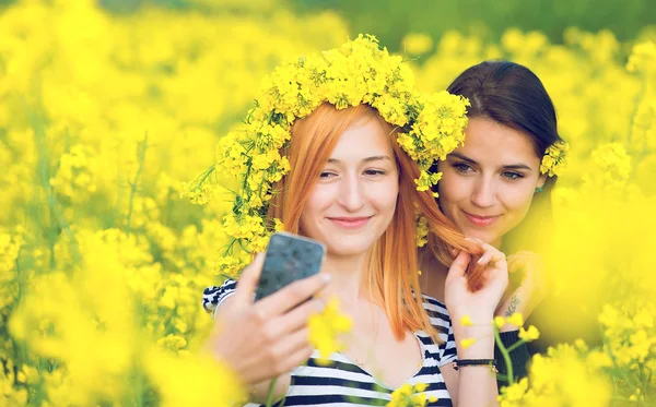 Due amici che si fanno un selfie in un campo con fiori gialli di colza — Foto Stock