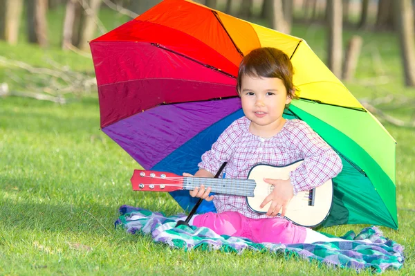 Petite fille heureuse avec un parapluie arc-en-ciel et guitare dans le parc — Photo