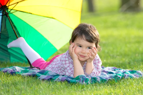 Bambina con ombrello arcobaleno nel parco — Foto Stock