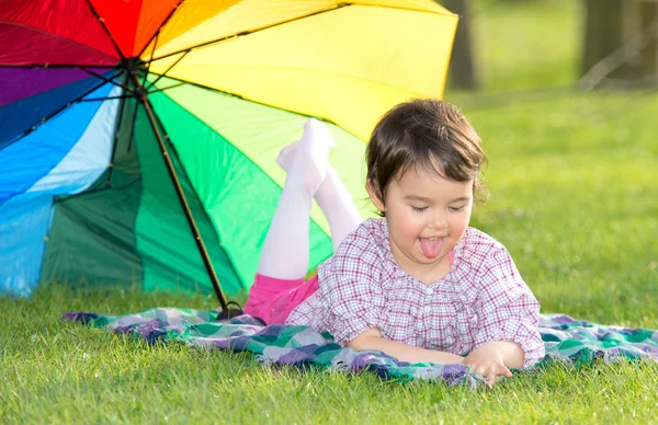 Kleines glückliches Mädchen mit Regenbogenschirm im Park — Stockfoto