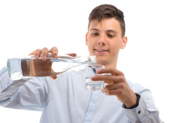 Genç garson cam şişe su üzerinde beyaz izole bir bardak içine dökme