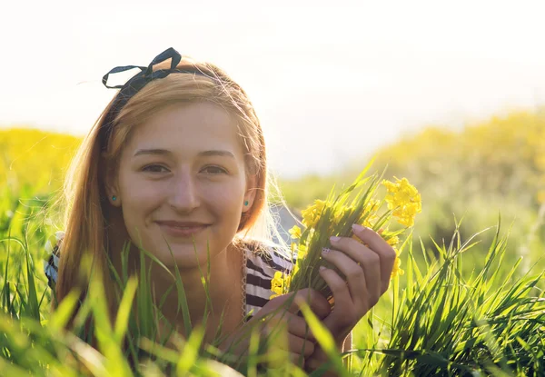 Nettes junges Mädchen inmitten eines Feldes mit gelben Blumen — Stockfoto