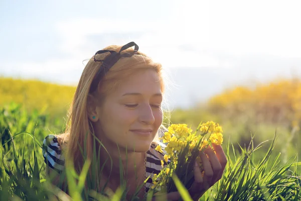 Menina bonito no meio de um campo de flores amarelas — Fotografia de Stock