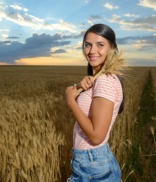 Portret pięknej młodej kobiety z kwiatami w polu pszenicy — Zdjęcie stockowe