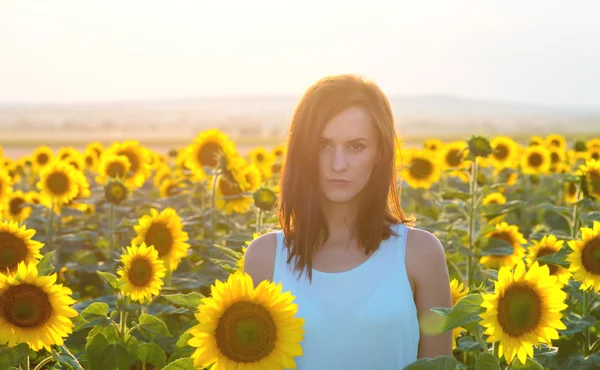 Frau im Sonnenblumenfeld bei Sonnenuntergang — Stockfoto