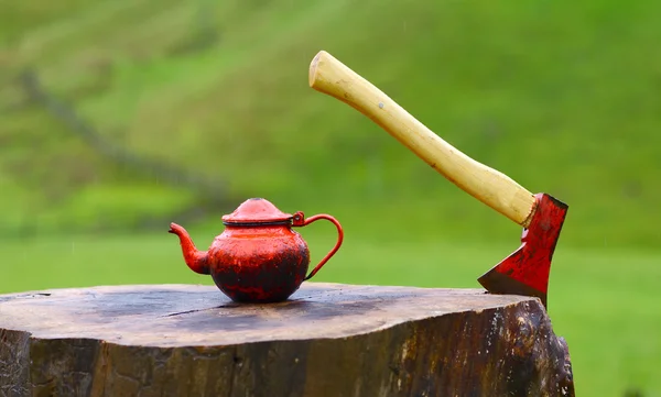 Топор для рубки дерева и красного чайника в летнем лагере — стоковое фото