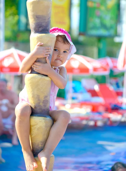 Ein lächelndes Kind klettert auf einen Baum. Falsche Palme im Aquapark — Stockfoto
