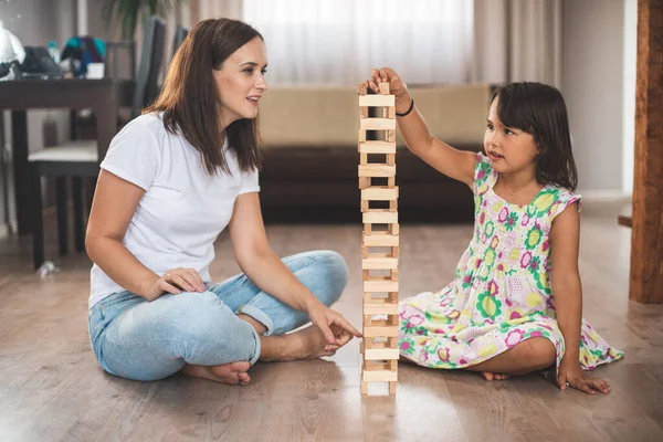 年轻的母亲和她的小女儿在木块上玩游戏 — 图库照片