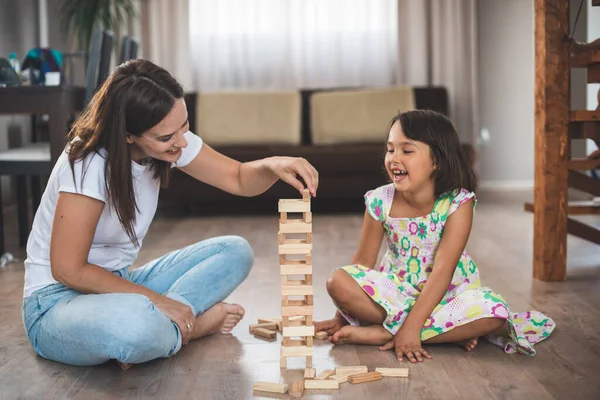 年轻的母亲和她的小女儿在木块上玩游戏 — 图库照片