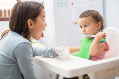Büyük ablası küçük kardeşini besliyor ve eğleniyor..