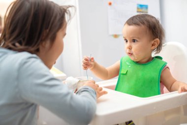 Büyük ablası küçük kardeşini besliyor ve eğleniyor..