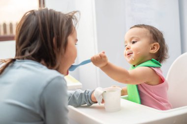Büyük ablası küçük kardeşini besliyor ve eğleniyor..