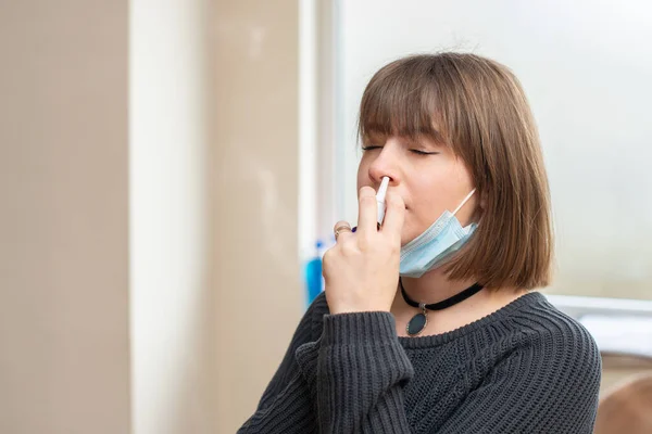 有病的年轻妇女在工作时使用鼻腔喷剂来保护自己免受考拉韦的侵害 — 图库照片