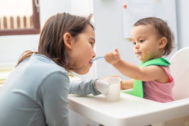 Büyük ablası küçük kardeşini besliyor ve eğleniyor..