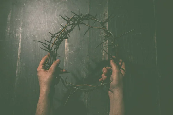 two hands hold crown of thorns