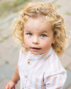 Mavi gözlü, kıvırcık sarı saçlı yakışıklı çocuk.