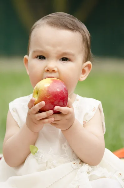 Söt liten flicka äter ett rött äpple — Stockfoto