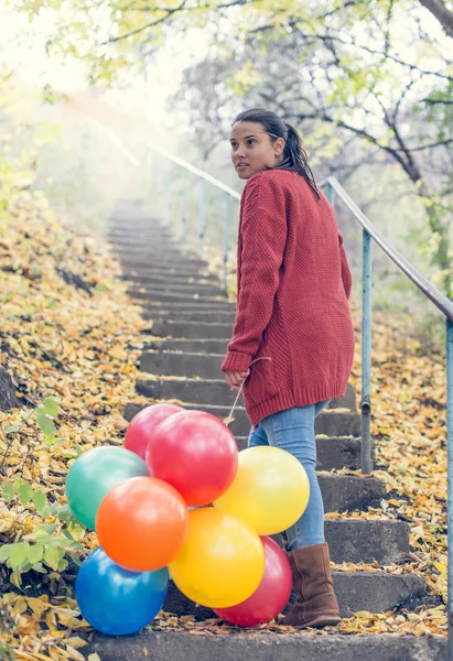 Beautiful girl with her balloons climbing stairs — Stock Photo, Image