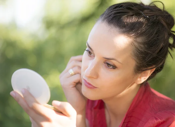 Beautiful woman loking in her pocket mirror — Stock Photo, Image