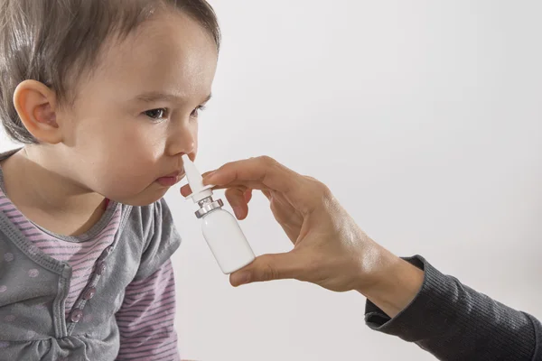 La mano de un padre de una niña aplica un aerosol nasal —  Fotos de Stock