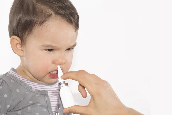 Bovenliggende de hand van een zieke meisje geldt een neusspray — Stockfoto